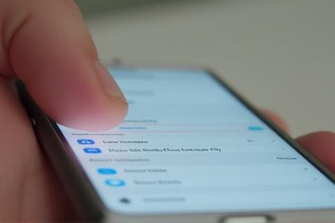 Hand holding an iPhone with settings menu open